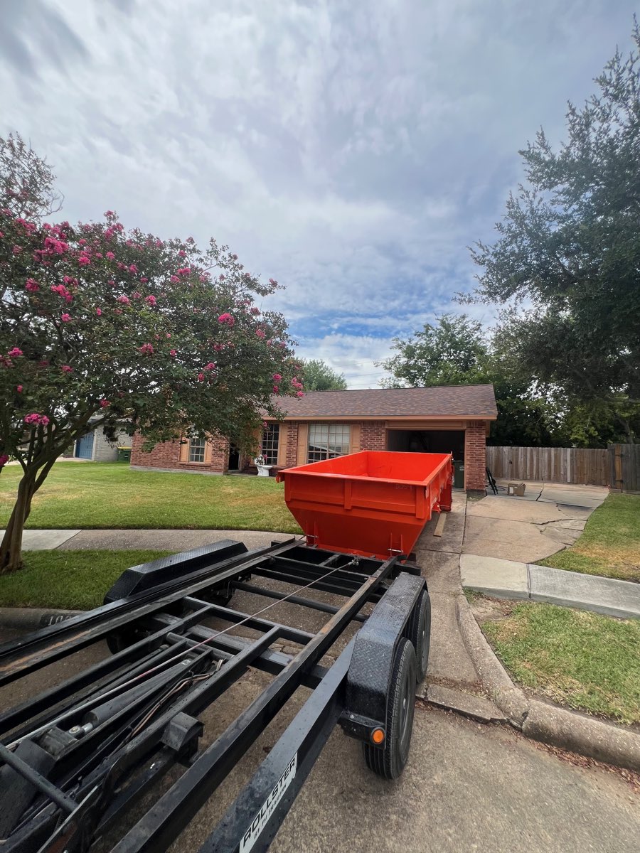 Roll-off dumpster dropped on a brick home driveway as the trailer pulls away