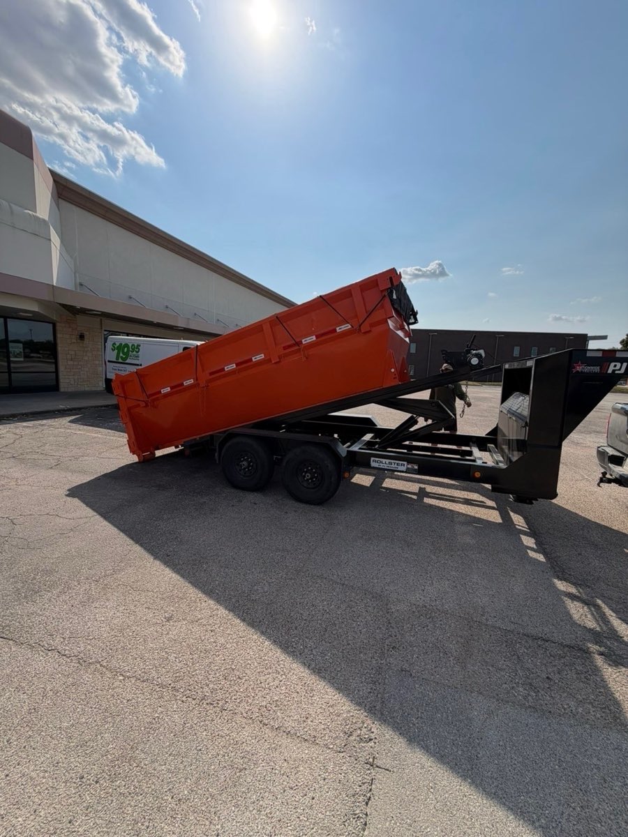 Roll-off dumpster rolling off the back of a PJ roll-off trailer